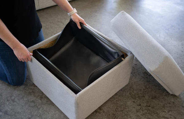 Person holding a liner for an ottoman’s hidden storage.
