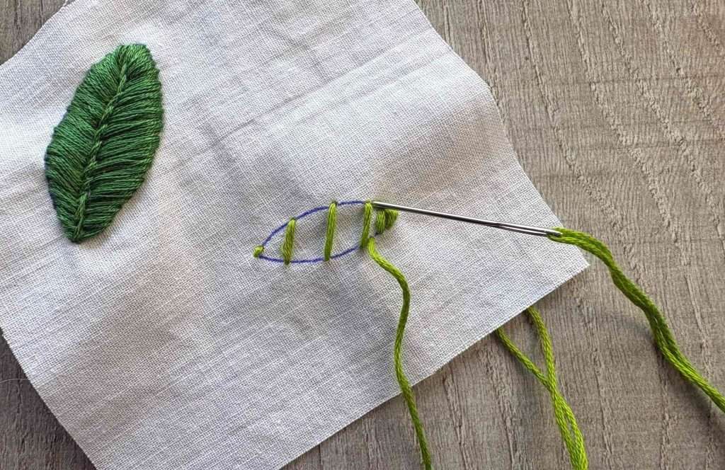 needle back down through fabric on green leaf shape